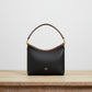 Black handbag with brown handle on a wooden table in an indoor setting
